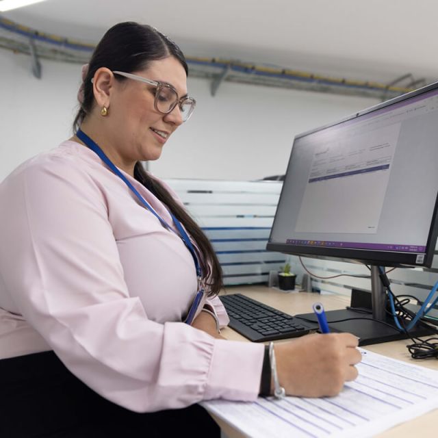 Mujer diligencia formulario de crédito en oficina Cajasan. Crédito con un propósito: bienestar financiero.