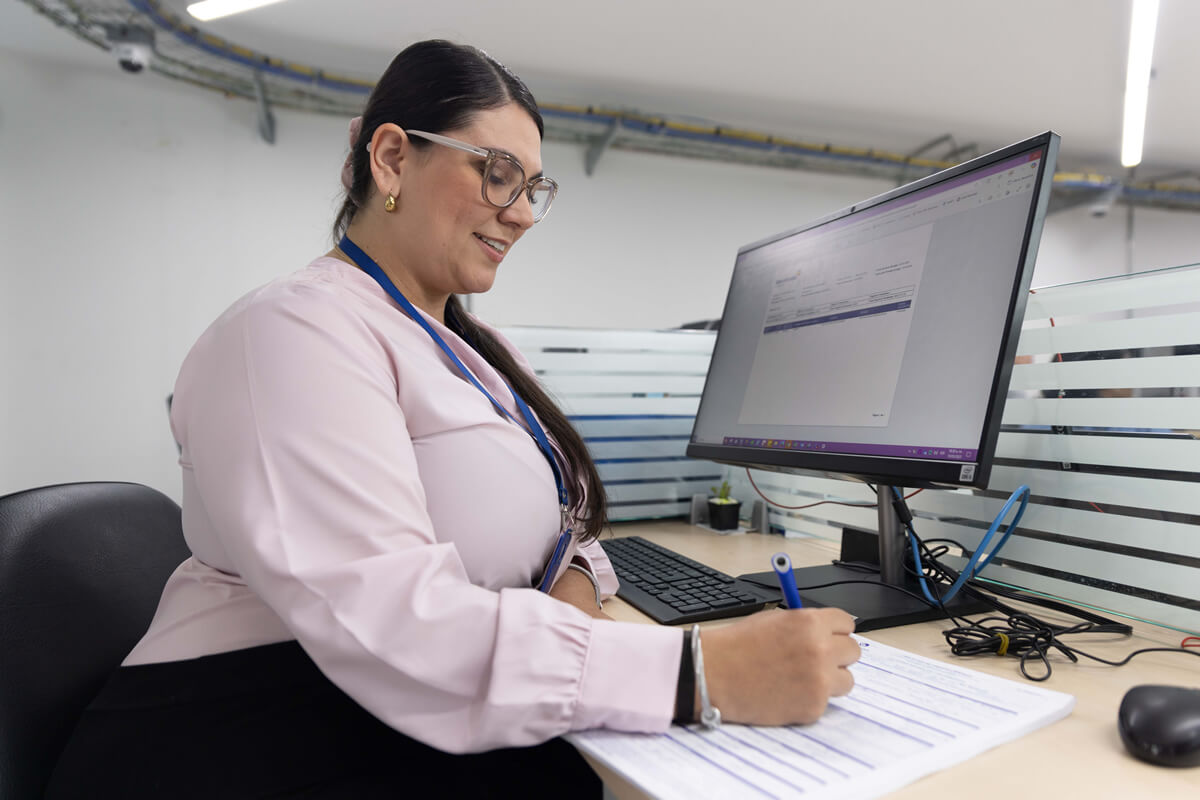 Mujer diligencia formulario de crédito en oficina Cajasan. Crédito con un propósito: bienestar financiero.