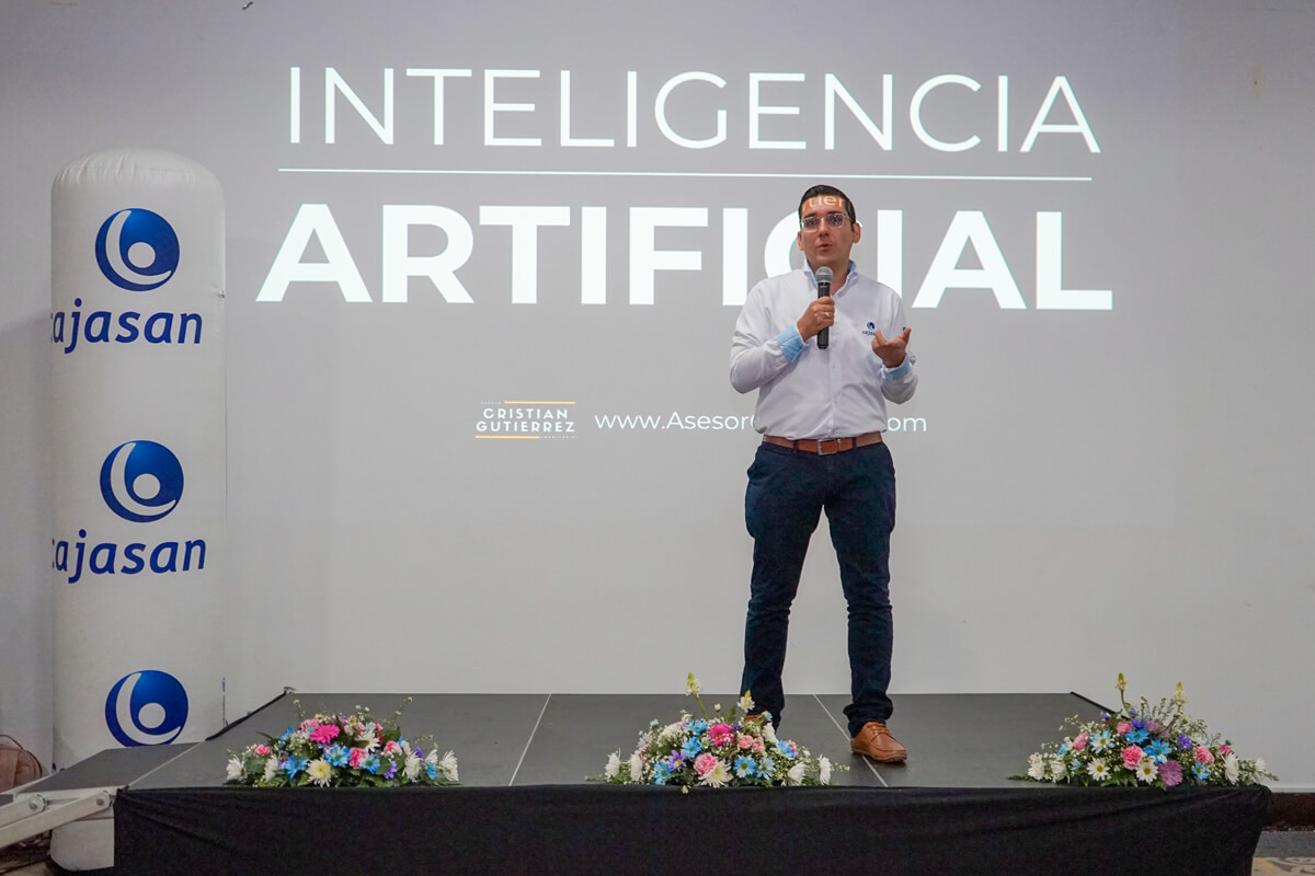 Conferencista presenta una charla sobre inteligencia artificial en un evento empresarial de Cajasan, frente a una pantalla con el título “Inteligencia Artificial”