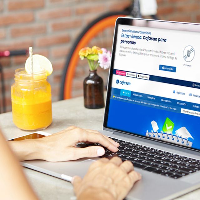 Persona navegando en el sitio web de Cajasan en una laptop.