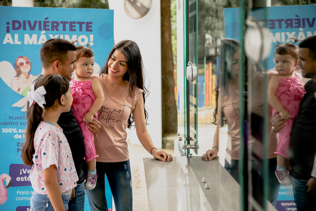 Familia sonriente en la taquilla de un centro recreativo Cajasan, lista para disfrutar beneficios y descuentos exclusivos gracias a las alianzas y convenios con marcas destacadas