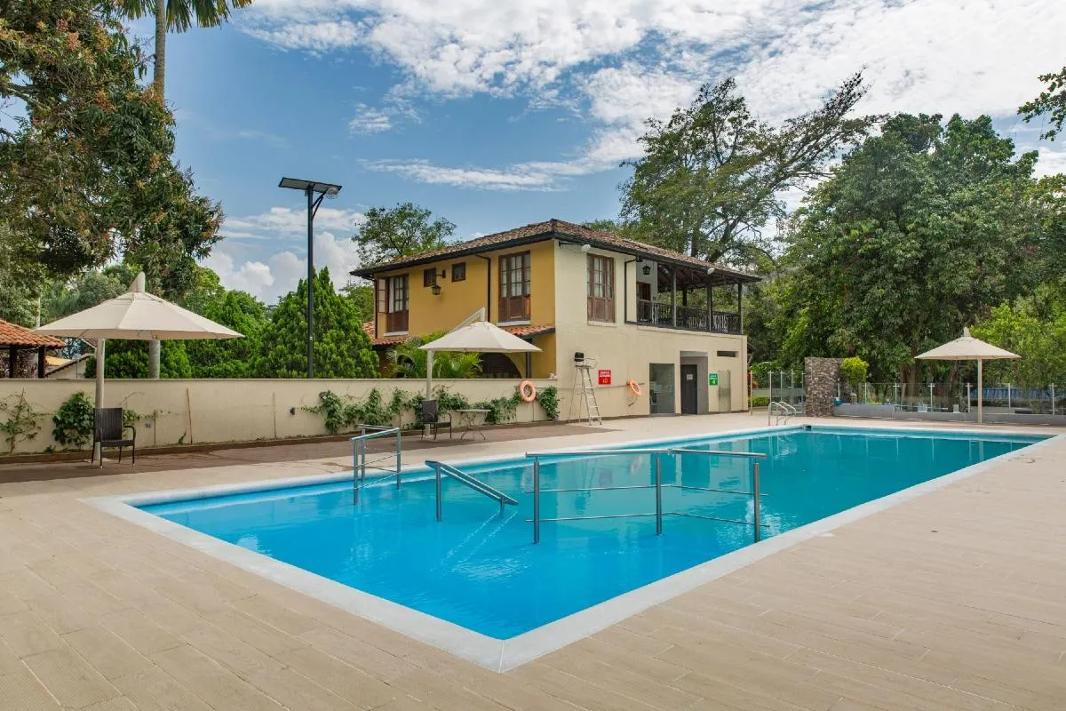 Piscina rodeada de un área de descanso junto a un edificio de estilo colonial.