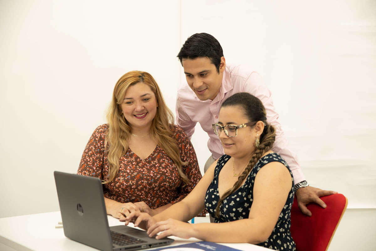 Personas trabajando en equipo frente a un computador portátil en sesión de capacitación